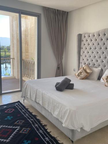 Schlafzimmer mit einem weißen Bett und einem großen Fenster in der Unterkunft Luxueux appartement Ritz Carlton Marina Smir in Sania Torres