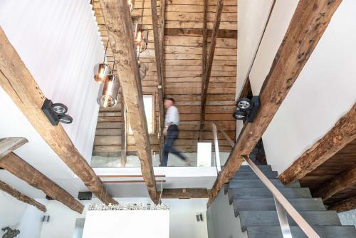 un hombre caminando por las escaleras en una habitación con techos de madera en MAISON de la Bonne Vie, en Thérondels