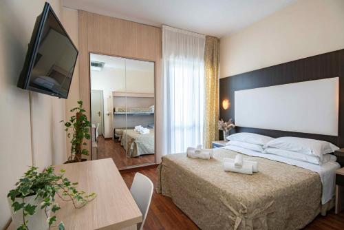 una camera con letto, televisore e tavolo di Hotel Baby B&B a Milano Marittima
