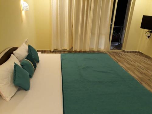 a bedroom with a bed with green and white pillows at Casa de joana deluxe in Calangute