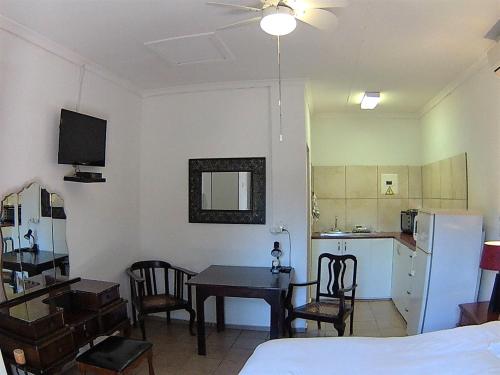 a living room with a table and a kitchen with a refrigerator at Kuru-Kuru Guesthouse in Kuruman