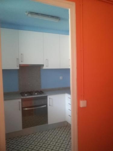 una cocina con armarios blancos y una puerta naranja en Pis Cèntric, en Manresa