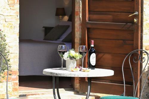 a table topped with a bottle of wine and a vase of flowers at L'Aia Country Holidays in Siena