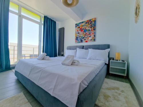 a bedroom with a large bed with a large window at SUNSHINE PLACE ApartHotel & Spa Mamaia Nord in Mamaia Sat/Năvodari