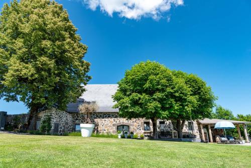 une maison en pierre avec deux arbres devant elle dans l'établissement MAISON de la Bonne Vie, à Thérondels