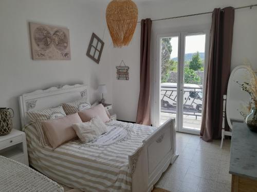 a bedroom with a bed with pink pillows and a balcony at Grande maison de caractere situee au cœur du village de de Roquefort des Corbières. Profitez de son grand jardin avec terrain de petanque barbecue et balancoire in Roquefort-des-Corbières