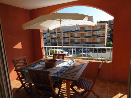 une table et des chaises sur un balcon avec un parasol dans l'établissement Spacieux T2 avec Loggia à 800m de la Plage, Parking et Forfait Ménage Inclus - Bormes-les-Mimosas - FR-1-610-12, à Bormes-les-Mimosas