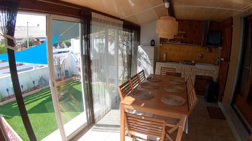 une salle à manger avec une table et une cuisine avec vue dans l'établissement Les margouillats - maisonnette à 2 pas de la plage, à Vias