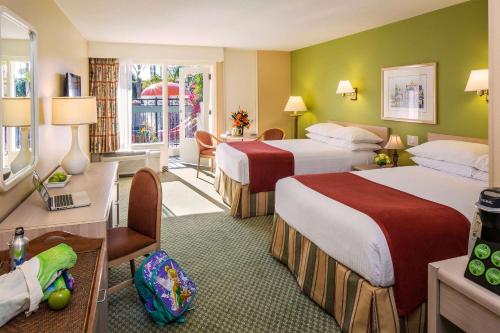 a hotel room with two beds and a desk at Howard Johnson by Wyndham Anaheim Hotel & Water Playground in Anaheim