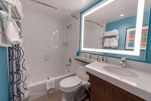 a bathroom with a toilet, sink and mirror at Howard Johnson by Wyndham Anaheim Hotel & Water Playground in Anaheim