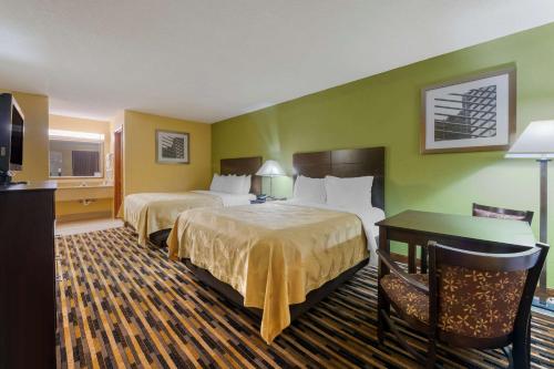 a hotel room with two beds and a desk at Quality Inn & Suites Mt Dora North in Mount Dora