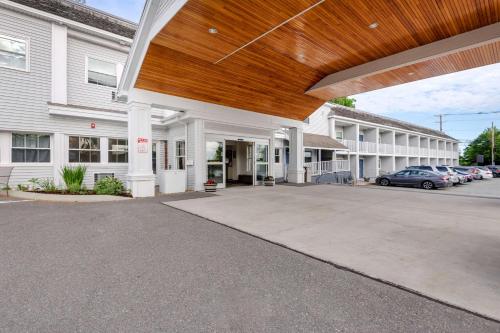 ein großes weißes Gebäude mit Autos auf einem Parkplatz in der Unterkunft Seasider Motel in Bar Harbor