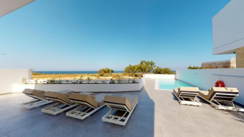 a patio with lounge chairs and a swimming pool at Periyiali Konnos Villas Beach Resort in Protaras