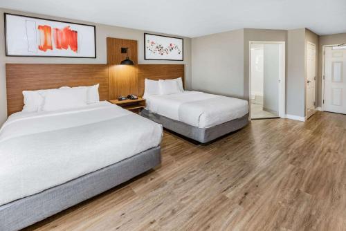 two beds in a hotel room with wooden floors at Hawthorn Extended Stay by Wyndham Ardmore in Ardmore