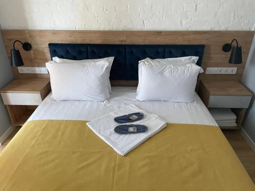 a bed with a yellow blanket with a pair of shoes on it at Partner Guest House in Kyiv