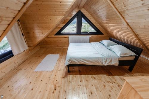 Ce lit se trouve dans une petite chambre dotée d'une fenêtre. dans l'établissement La Cabană, à Vişeu de Jos