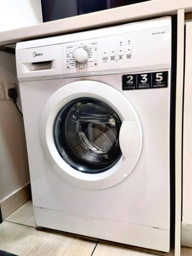a white washing machine sitting in a kitchen at Almas Family Studio 100mbps Netflix By STAY in Nusajaya