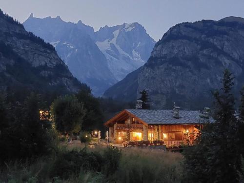 a log cabin with mountains in the background at night at Hotel Lo Campagnar in Courmayeur