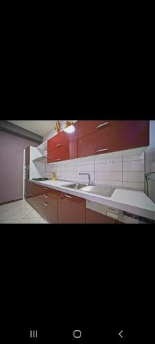 una cocina con armarios rojos y blancos y fregadero en Apartman Monaco, en Makarska
