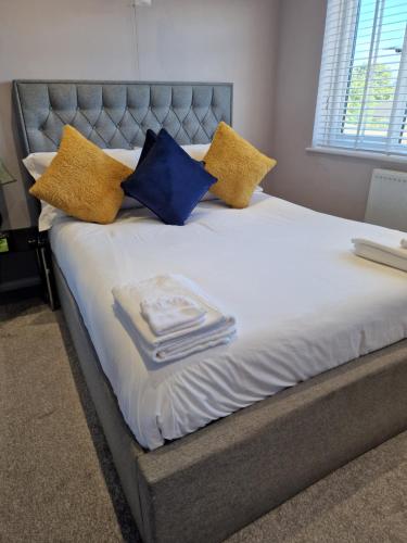 a bed with yellow and blue pillows on it at Linx View 4 Bedroom House in Kent