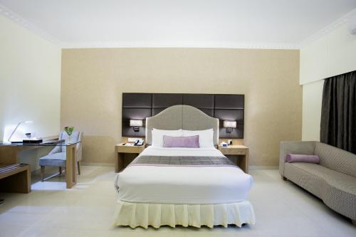 a bedroom with a bed and a desk and a couch at Ascott Palace Dhaka in Dhaka