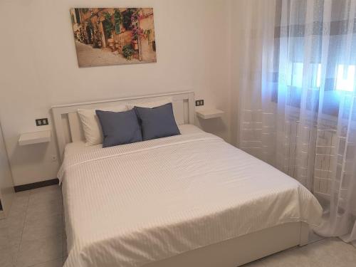 un letto bianco con cuscini blu in una camera da letto di Rosolina (Paese) Apartment a Rosolina