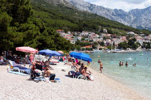 a group of people sitting on a beach at Apartments with a parking space Brela, Makarska - 17371 in Brela