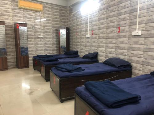 una habitación con 4 camas alineadas contra una pared de ladrillo en Charyana Backpackers en Ahmedabad