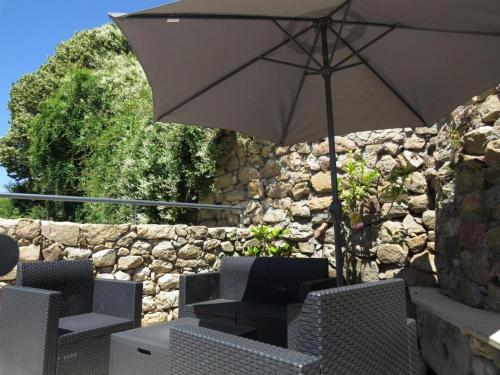 a table and chairs with an umbrella in front of a stone wall at Casa da Roda - Turismo de Habitação in Pinhel