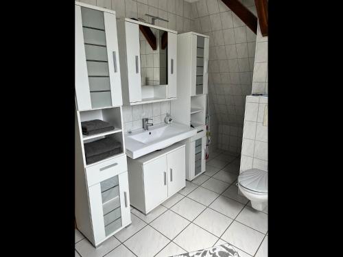 a white bathroom with a sink and a toilet at Moderne FeWo Zum Gremminer See in Gräfenhainichen