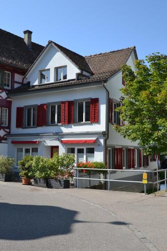 a white building with red shutters on a street at Bachperle in Steckborn