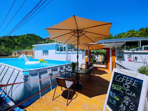 a patio with a table and an umbrella next to a pool at 北京城涛小筑客栈 Chengtiao Xiaozhu in Miyun