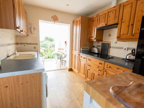 a kitchen with wooden cabinets and a large window at Pass the Keys Cosy cottage with views over the Shropshire hills in Ludlow