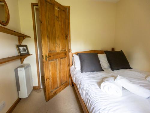 a bedroom with a bed and a wooden door at Pass the Keys Cosy cottage with views over the Shropshire hills in Ludlow