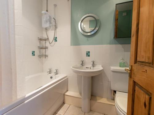 a bathroom with a sink and a tub and a toilet at Pass the Keys Cosy cottage with views over the Shropshire hills in Ludlow