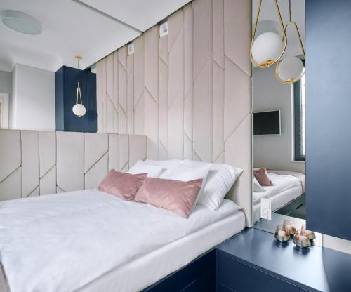 a bedroom with a large white bed with pink pillows at Apartament Zamojski Rynek in Zamość