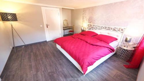 ein Schlafzimmer mit einem großen Bett mit roten Kissen in der Unterkunft Haus8 – dein Genussferienhaus in Mettlach