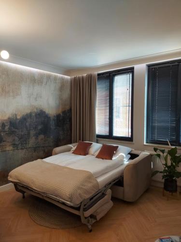 a bedroom with a large bed and two windows at Apartament Zamojski Rynek in Zamość