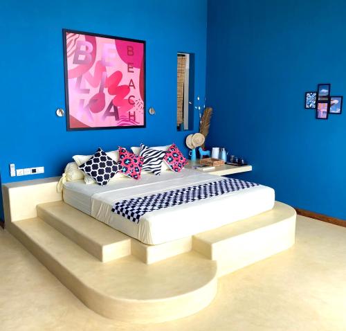 Bett in einem Zimmer mit blauer Wand in der Unterkunft Belika Beach Club in Hiriketiya