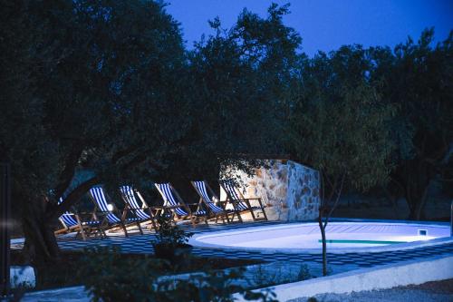 a group of chairs sitting around a pool at night at Apartments Olea in Biograd na Moru