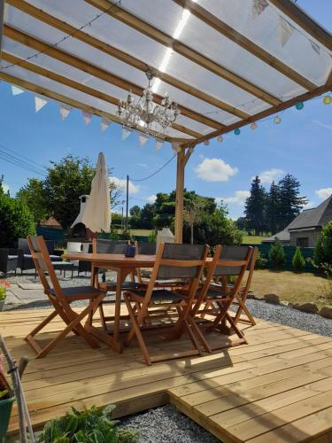 a wooden deck with a table and chairs under a pergola at La Jolie Petite Maison for groups 1-5 in Fontenermont