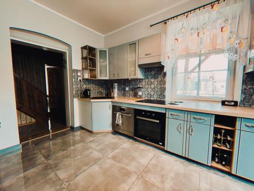 a large kitchen with blue cabinets and a window at Agroturystyka Szerokopaś in Nidzica