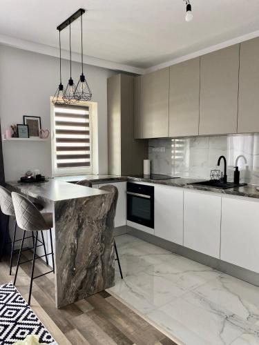 a kitchen with white cabinets and a marble counter top at Velvet Studio in Târgu-Mureş