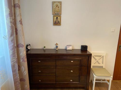 a bedroom with a dresser with a clock on the wall at Oli's Mountain Apartment in Buşteni