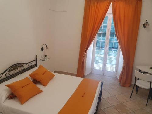 a bedroom with a bed with orange pillows and a window at Casal Duca in Taranto