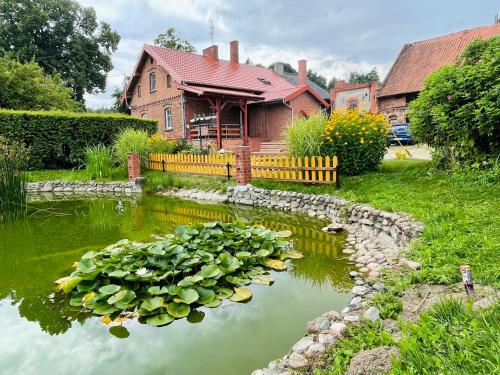 a pond in front of a house with lilies in it at Agroturystyka Szerokopaś in Nidzica