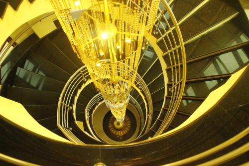 a spiral staircase with a gold chandelier at hotel bessota international in Thiruvalla