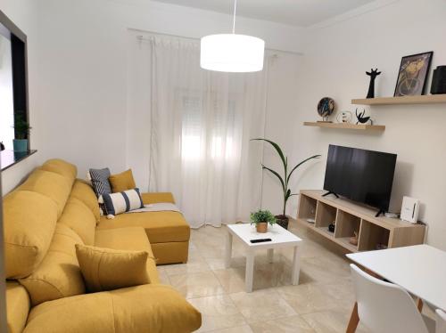ein Wohnzimmer mit einem gelben Sofa und einem TV in der Unterkunft La Brisa apartamento in Málaga
