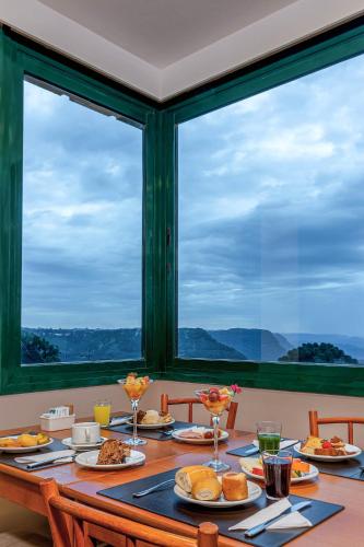 un tavolo con piatti di cibo sopra con finestre di Hotel Laghetto Toscana a Gramado