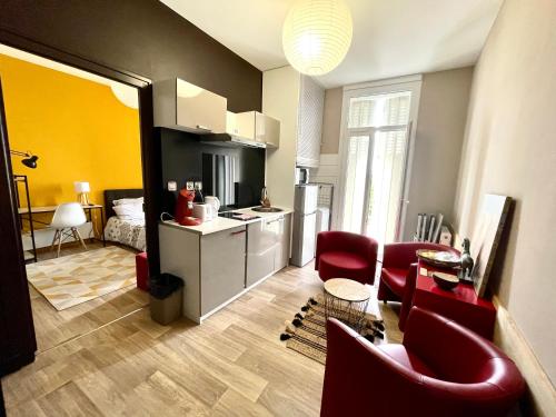 a kitchen and living room with red chairs and a table at La Terrasse du Colombier 1er étage in Limoges